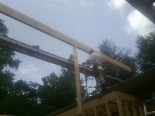 Carpenter setting a ridge beam over a new addition frame — Ice Dam Removal by Roofing Brothers in Swan Lake