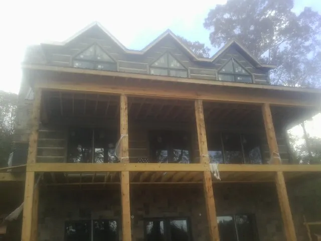 Dormers and porch framing on a large log home under construction — Roof Coating work by our crew in Swan Lake