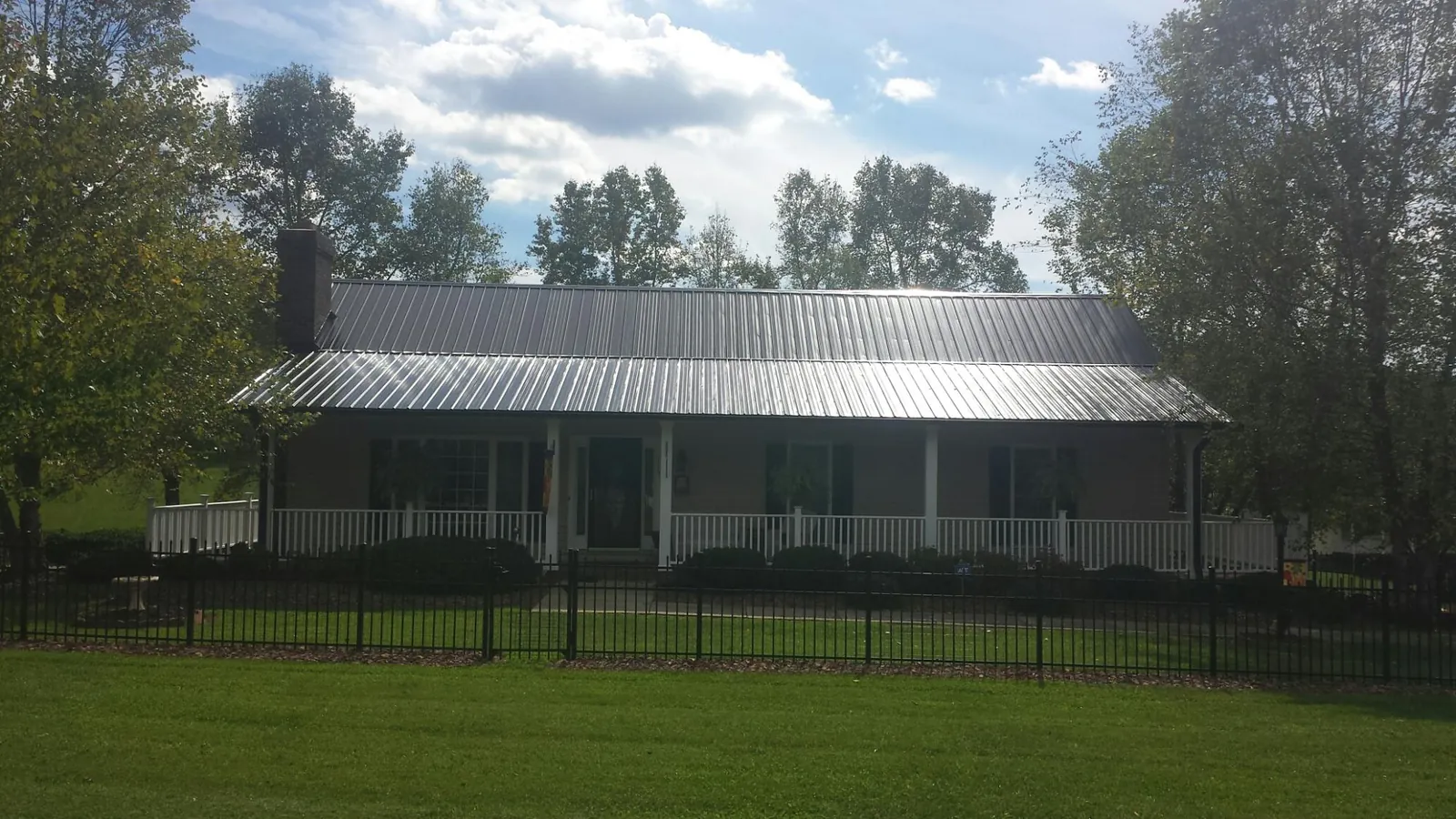 Gray metal roof on a brick ranch with a full width front porch in Swan Lake