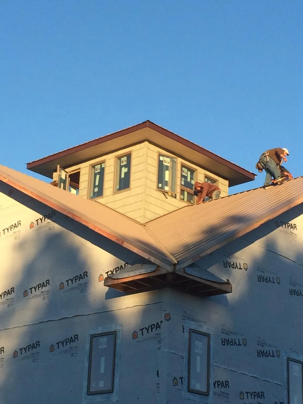 Roofers working around a rooftop cupola on a new metal roof at sunset — Roof Waterproofing in Swan Lake by Roofing Brothers